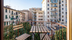 Un balcon avec une table et des chaises en bois, entouré d’immeubles d’habitation.