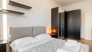 Une chambre à coucher moderne, comprenant un lit, des tables de chevet, une commode, une lampe et une armoire.