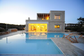 Une maison moderne dotée d’une piscine, d’un patio couvert et offrant une vue sur le paysage environnant.