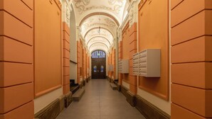 A long, narrow hallway with ornate ceiling details and a central door at the end.
