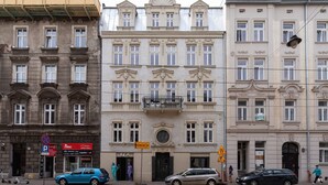 A multi-story building with a central balcony, a storefront with mannequins, and a parked car.