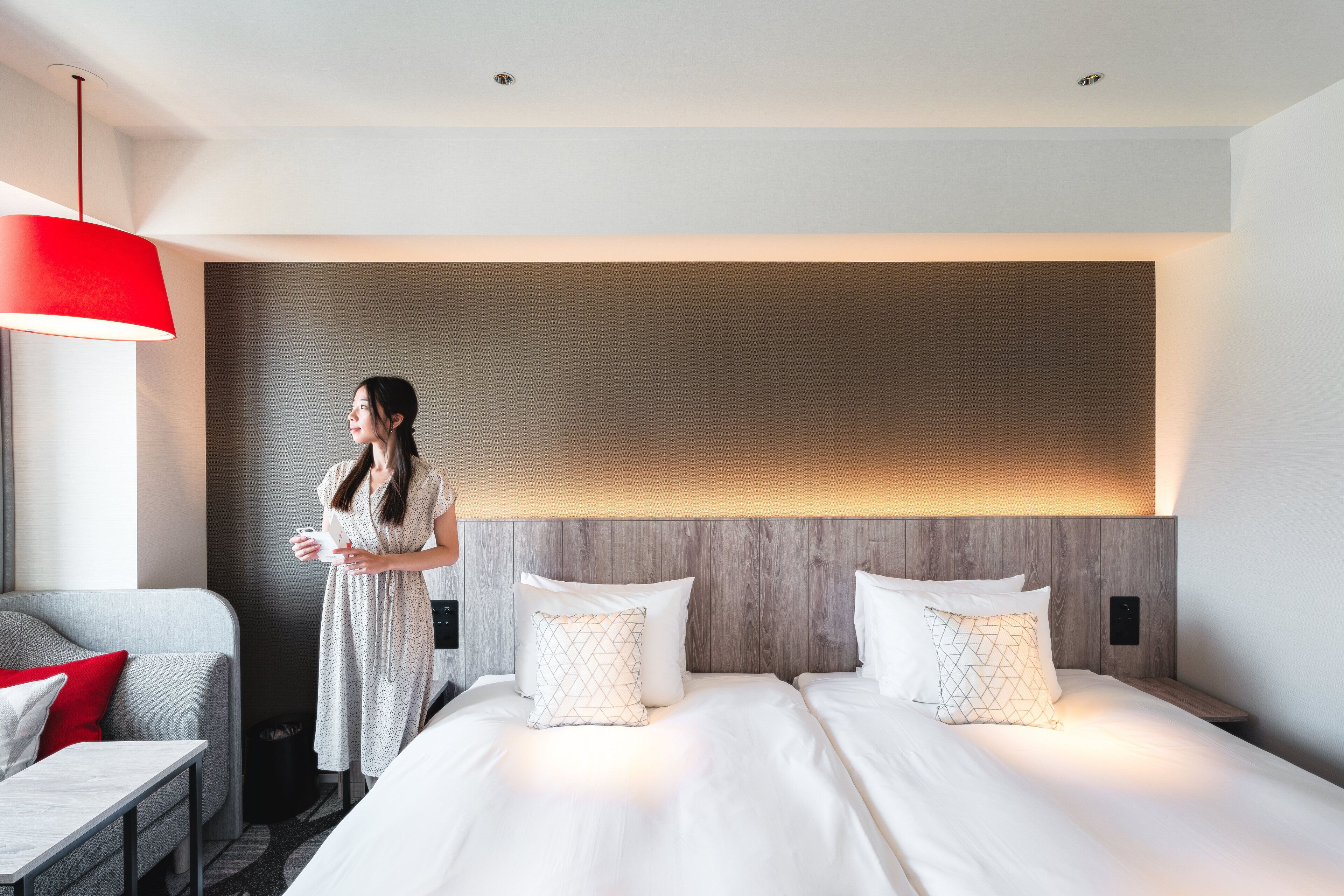 Una habitación de hotel con una cama grande, una mesita de noche, un escritorio y una lámpara roja.
