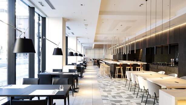 A modern restaurant with a long counter, black pendant lights, and a patterned floor. - Hotel JAL City Toyama (Toyama)