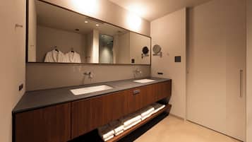 A modern bathroom with two sinks, a large mirror, and wooden cabinetry.