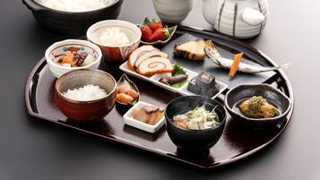 Presentación tradicional de comida japonesa con diversos platos y utensilios sobre una bandeja.