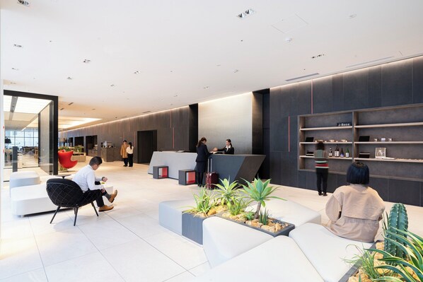 A modern reception area with a reception desk, seating arrangements, and a display shelf with items.