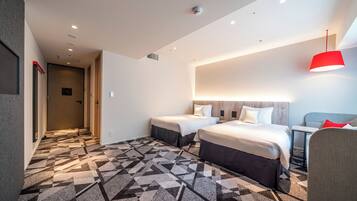 A hotel room with two beds, a patterned carpet, a red pendant light, and a hallway with a door.