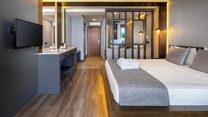 A modern hotel room with a large bed, a desk, and a television. - Adora Calma Beach Hotel - Adults Only (Manavgat)