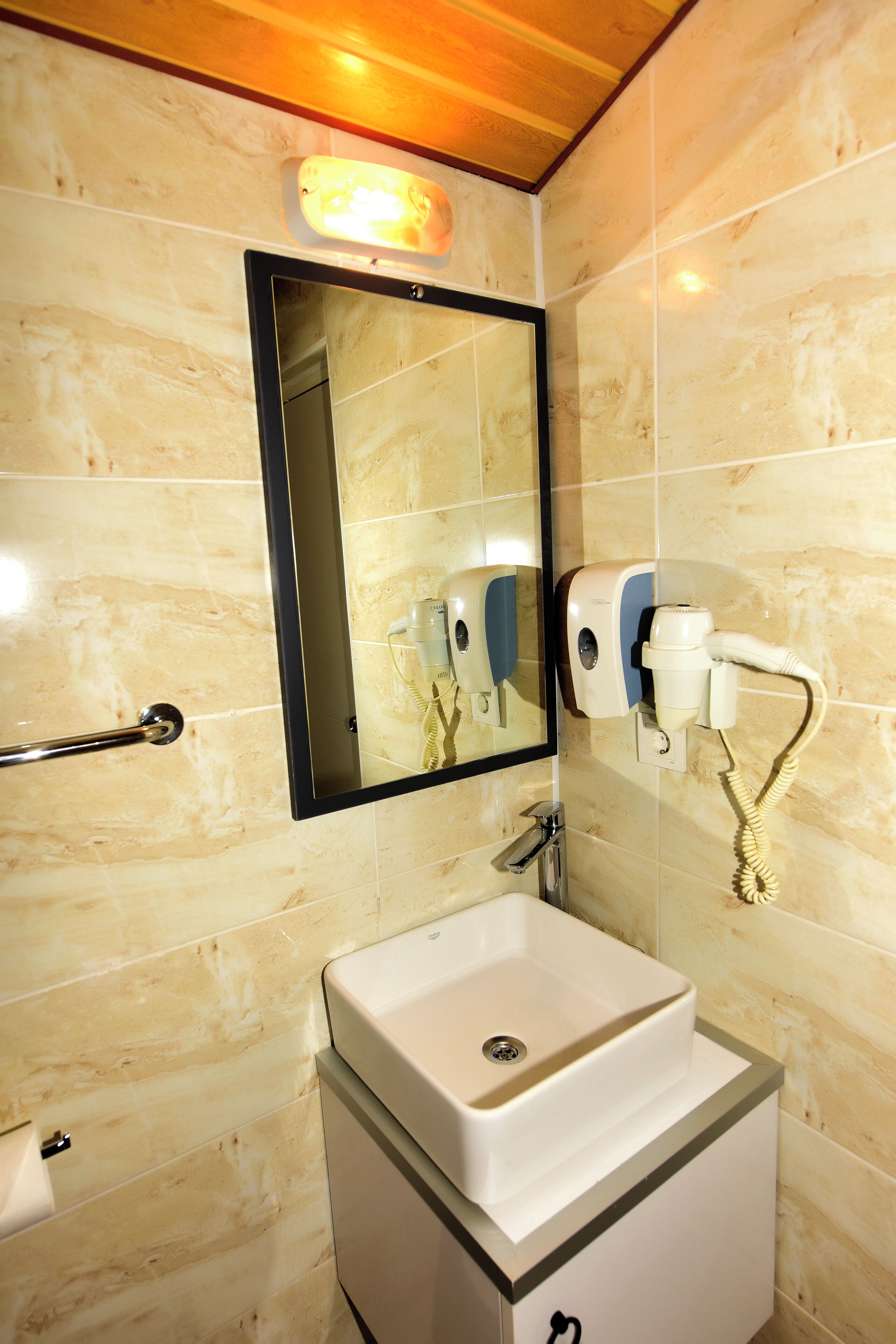 Baño con lavamanos, espejo, dispensador de toallas y secamanos.