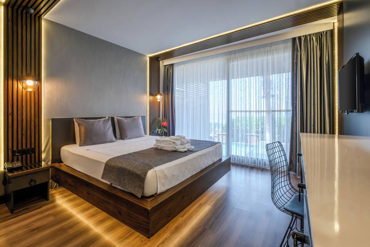 Una habitación de hotel moderna con una cama grande, una mesita de noche y un escritorio con silla.