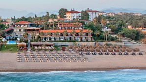 A beachfront hotel with multiple buildings, a pool, and numerous sun loungers on the beach. - Adora Calma Beach Hotel - Adults Only (Manavgat)