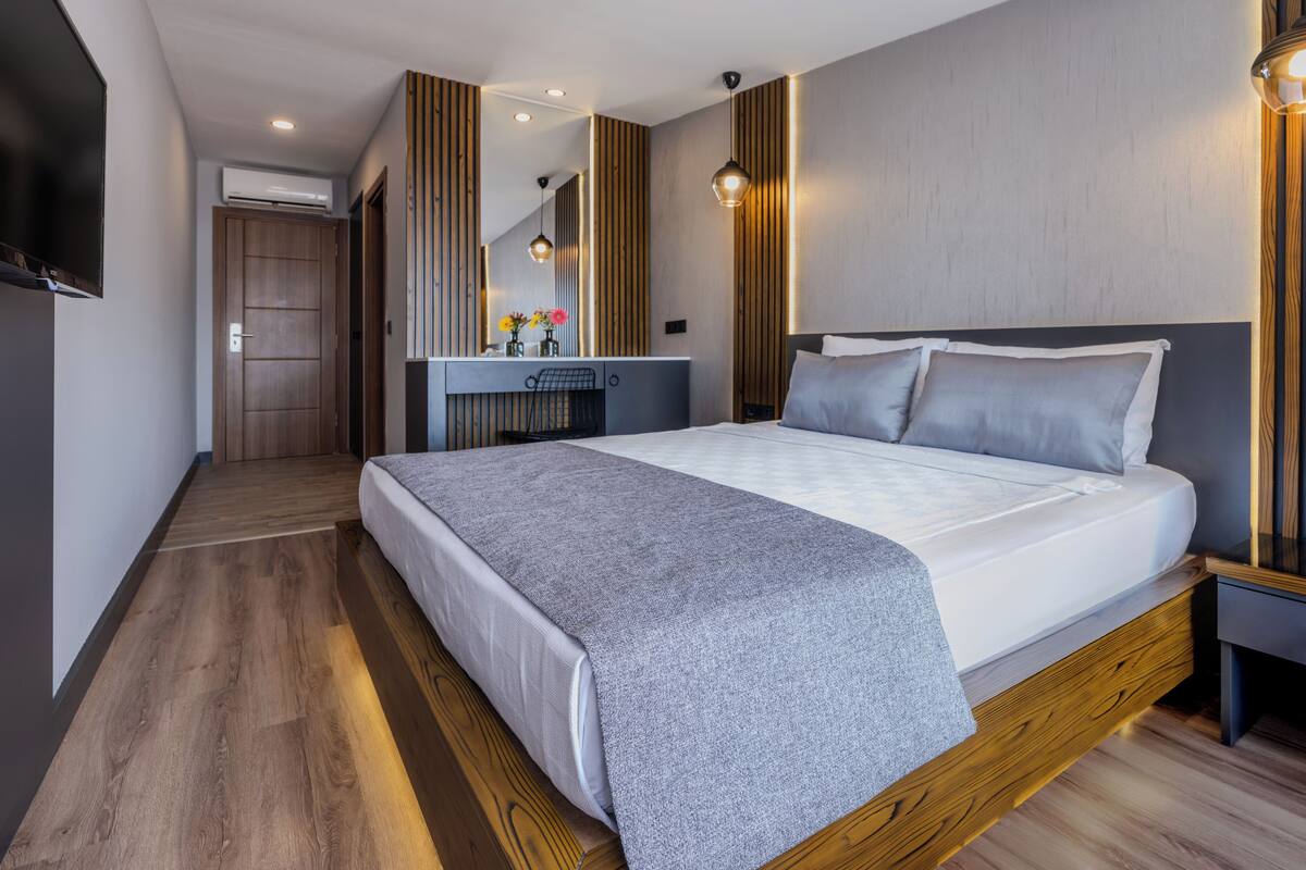 Un dormitorio moderno con una cama grande, cabecera de madera y una mesita de noche.
