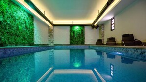 An indoor swimming pool with a tiled floor, green wall, and lounge chairs. - Nacho Hotel Yerevan By One (Yerevan)