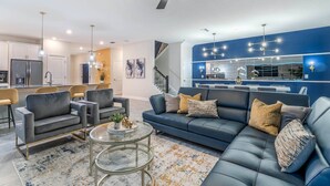 A modern living room with a blue accent wall, a dark blue sofa, and a glass coffee table.