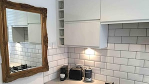 Una cocina moderna con armarios blancos, estufa a gas, cafetera y tostadora.