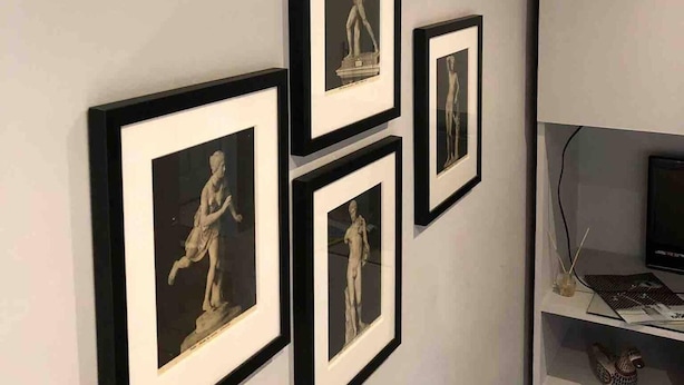 Una pared con cuatro fotografías blanco y negro enmarcadas de esculturas.