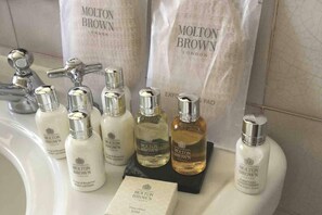 A bathroom sink with multiple bottles of Molton Brown products, including body lotion, body lotion, and conditioner. - Remarkable Apartment Near London Tower Bridge (London)