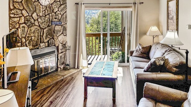 Ein Wohnzimmer mit Steinwand, Kamin, einer Couch und Blick durch große Glasüren.