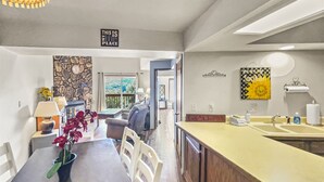 Eine moderne Küche mit Kochinsel, einem Essbereich mit Tisch und Stühlen sowie einem Wohnzimmer mit Sofa und einer Wand aus Stein.