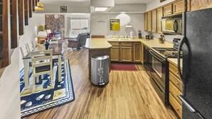 Eine moderne Küche mit Holzausstattung, einem Kühlschrank und einer Essecke mit Tisch und Stühlen.