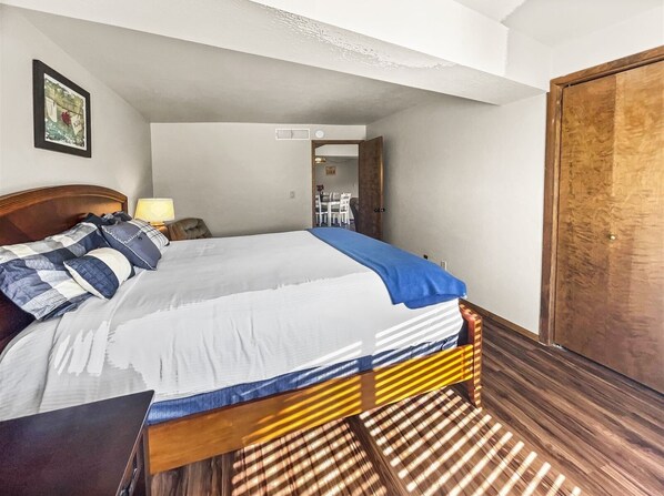 Una cama bien hecha con un edredón a rayas, un cabecero de madera y una mesita de noche con una lámpara.