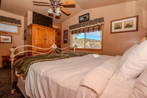 A bedroom with a bed, wooden wardrobe, and a ceiling fan.