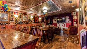 Un restaurante con mesas y sillas de madera, una pared decorada con motivos de granero en rojo y blanco, y diversas fotografías y discos enmarcados en las paredes.