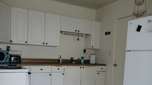 Una cocina con armarios blancos, un microondas, un fregadero y un refrigerador.