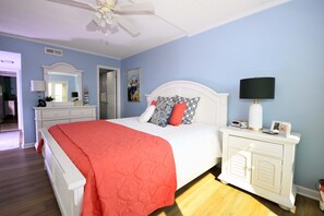 A bedroom with a bed, nightstand, dresser, and a ceiling fan. - Come and enjoy your vacation at this stylish, oceanfront, 2 bedroom condo located in midtown and just couple steps away from the beach! (Ocean City)