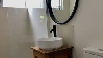 Une salle de bain avec un lavabo blanc, un meuble-lavabo en bois et des toilettes.