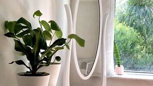 Une pièce avec une coiffeuse blanche, un grand miroir et deux plantes en pot.