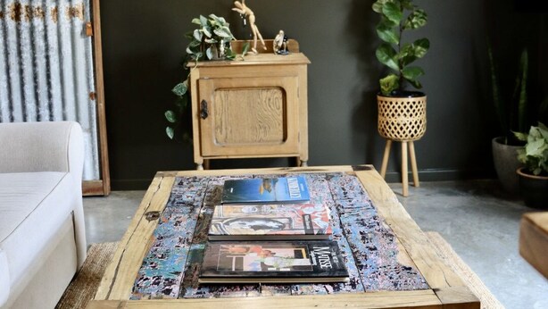 Un salon comprenant une table basse sur laquelle sont disposés des magazines, un canapé, un meuble décoratif et une plante en pot.