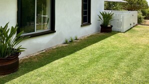 Une maison moderne avec un toit plat, deux fenêtres et une clôture blanche.