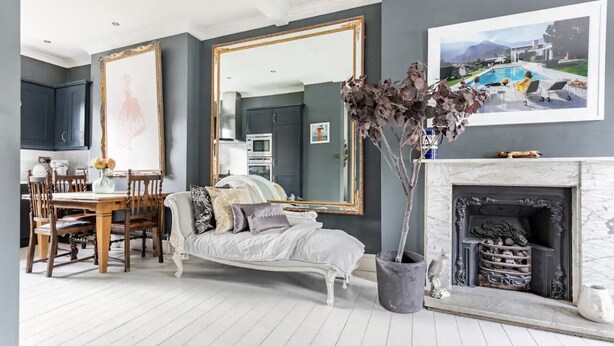 A living room with a dining area, a fireplace, and a large mirror.