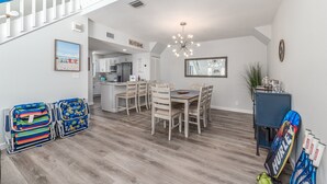 Un comedor amplio con una mesa y sillas de madera, una escalera y vistas a la cocina.
