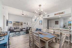 A modern living room with a dining area, a staircase, and a kitchen.