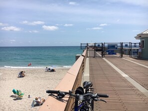 A beach with a wooden boardwalk, a bicycle, and a flag.