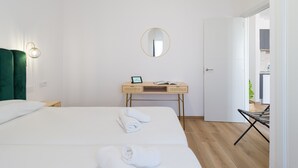Camera d'albergo con due letti, una scrivania con un portatile, uno specchio e una porta che dà su un bagno.