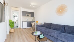 Un soggiorno moderno con un divano grigio, un tavolino rotondo con un tablet e una pianta in vaso.