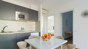 A modern kitchen with a built-in microwave, a sink, and a dining area with a table and chairs. - Modern apartment. Swimming pool and beachfront. Corralejo (Corralejo)