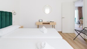 A hotel room with two beds, a desk with a mirror, and a view of the dining area. - Modern apartment. Swimming pool and beachfront. Corralejo (Corralejo)