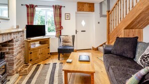Ein gemütliches Wohnzimmer mit Kamin, Fernseher, einer Couch und einer Holztreppe.