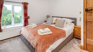 Ein Schlafzimmer mit einem großen Bett, einem Fenster mit Vorhängen, einem Heizkörper und einer Holztür.