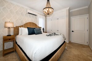A bedroom with a bed, bedside table, lamp, wardrobe, and a chandelier. - Designer 6BR Pool Villa in Gated Tierra del Sol (Noord)