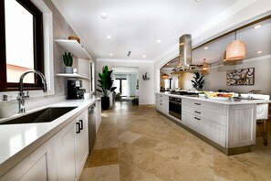 A modern kitchen with a large island, white cabinetry, and a view to the living area.