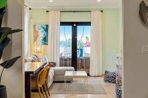 A hotel room with a dining area, a sofa, a small table, and a view through the door. - Designer 6BR Pool Villa in Gated Tierra del Sol (Noord)