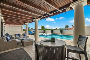 An outdoor patio with a pool, seating area, and a clear view of the sky.