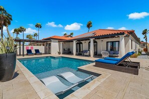 A swimming pool with lounge chairs and a covered patio area.