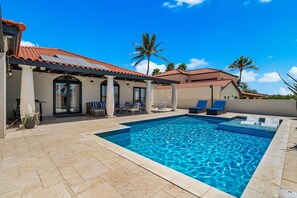 A swimming pool with a tiled deck, lounge chairs, and a covered patio area. - Designer 6BR Pool Villa in Gated Tierra del Sol (Noord)