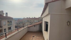 A narrow balcony with a tiled floor, a metal railing, and a small window.